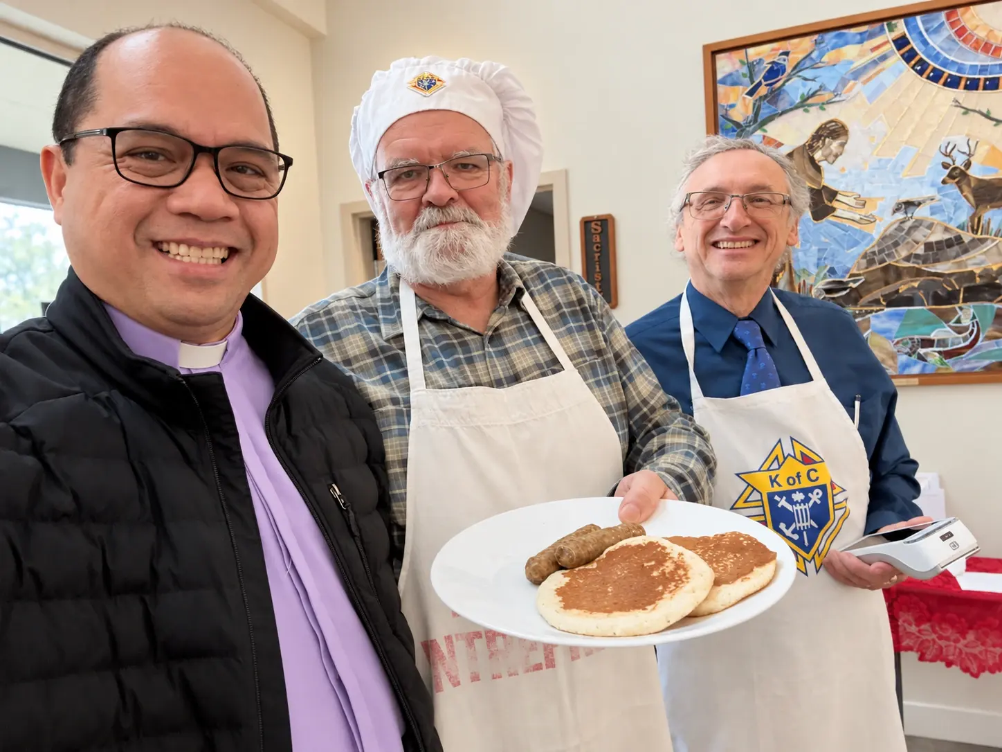 Father Mel smiling with parish volunteers at a community pancake breakfast